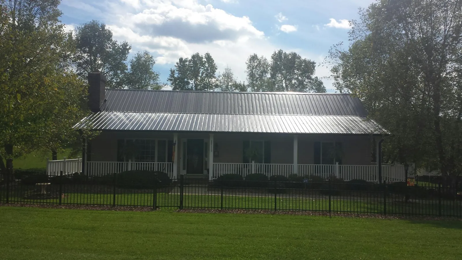 Gray metal roof on a brick ranch with a full width front porch — Gutter Guard Installation work by our crew in Brownsboro