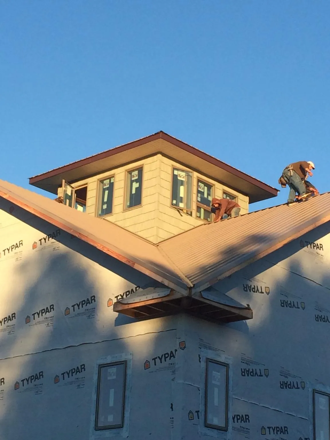 Roofers working around a rooftop cupola on a new metal roof at sunset — Roof Waterproofing in Brownsboro by Roofing Brothers